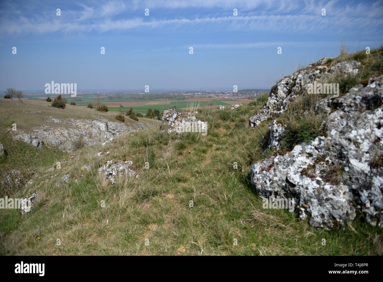 16 aprile 2019, il Land della Baviera, Nördlingen: Dietro aspre rocce si trova la piana del cratere Ries con Daniel chiesa torre della città di Nördlingen. Il Nördlinger Ries, formata da un meteorite impatto, roccia ha delle strutture simili a quelle che si trovano sulla luna. Pertanto la NASA ha inviato la sua astroauts a nord di Svevia per preparare la luna missioni di carico. Foto: Stefan Puchner/dpa Foto Stock