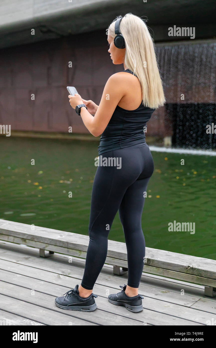 Vista posteriore della donna runner avviare la musica sullo smartphone prima di eseguire Foto Stock