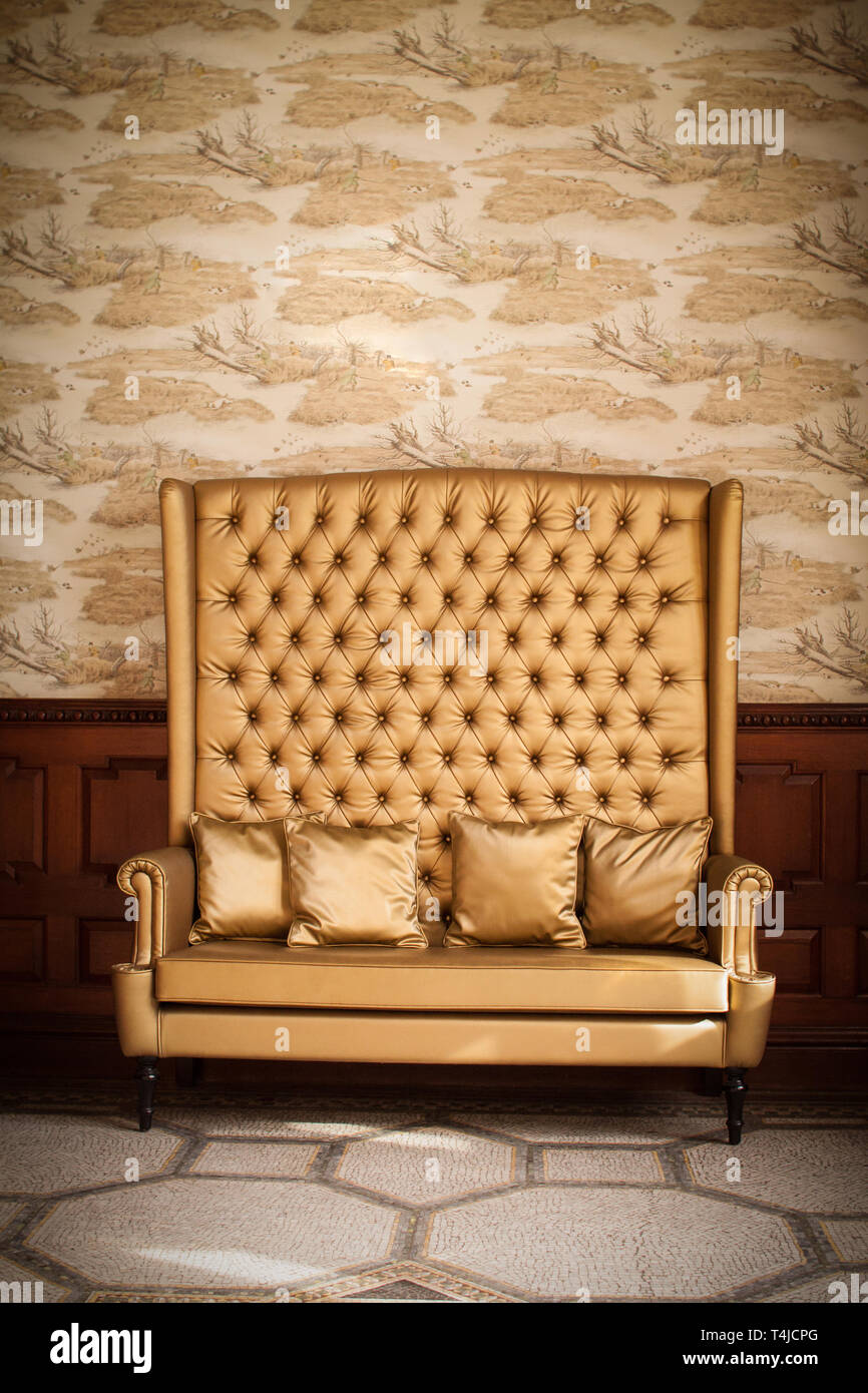 A schienale alto divano oro con cuscini, Scozia Foto Stock