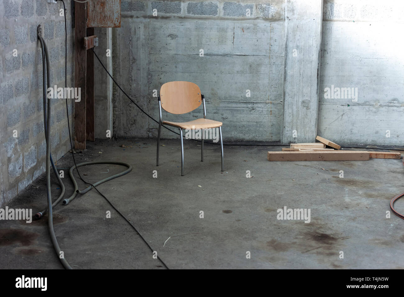 Una sedia solitaria nell'angolo di abbandono di un edificio in calcestruzzo Foto Stock