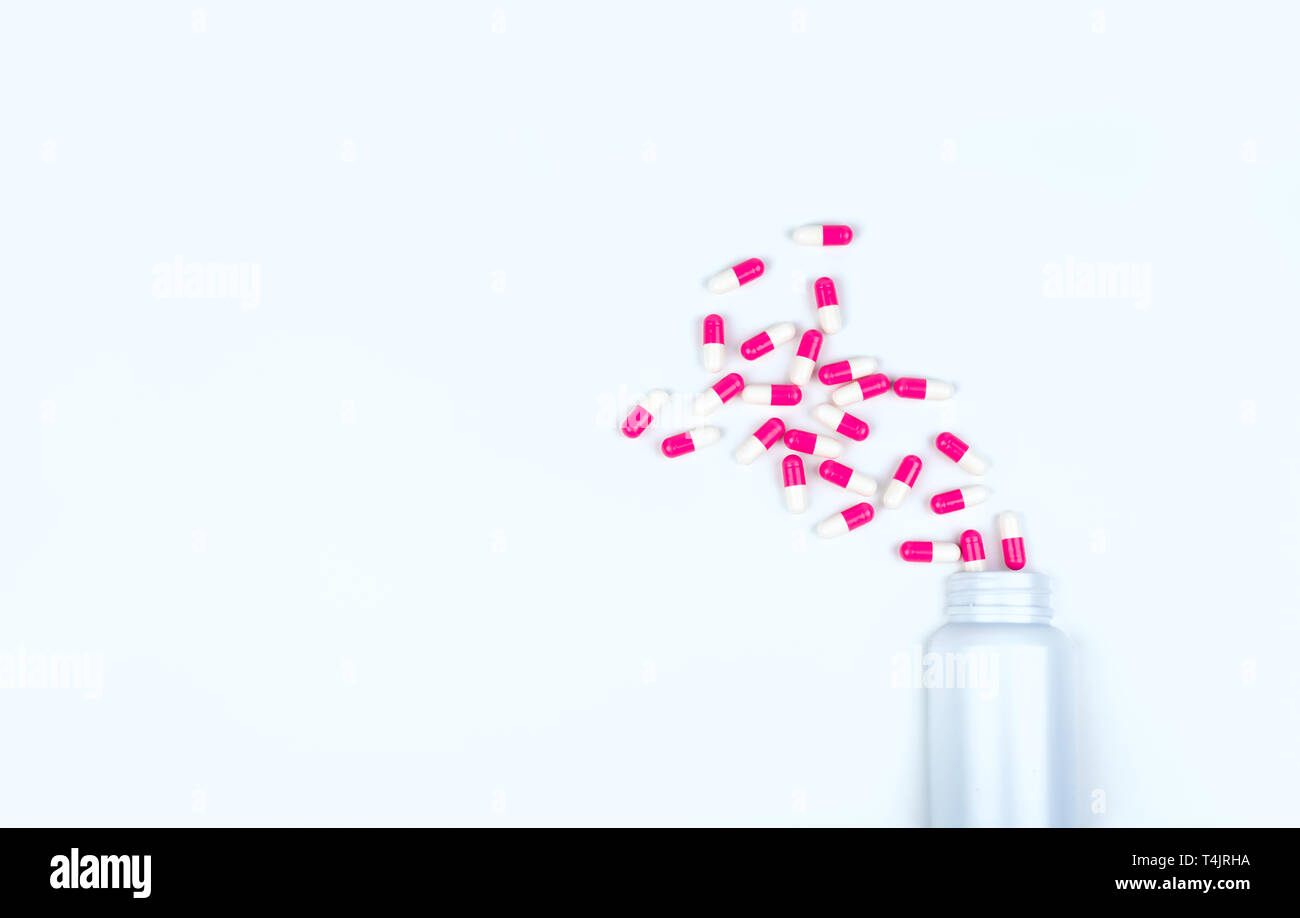 Rosa-bianco capsula di antibiotico pillole sparse fuori di plastica bianca flacone di farmaco. Farmaco antibiotico resistenza concetto. Farmaci antibiotici utilizzare. La salute globale Foto Stock
