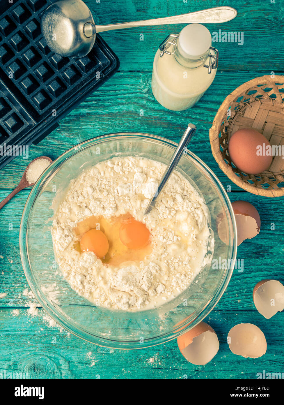 Rendendo le cialde a casa - waffle ferro, l'impasto in un recipiente e ingredienti - latte, uova e farina. Foto Stock