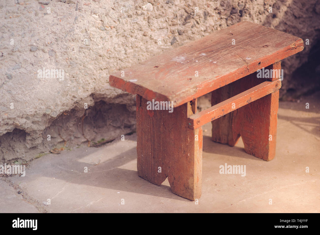 Il vecchio legno bruno Sgabello basso in cantiere con la luce solare Foto Stock