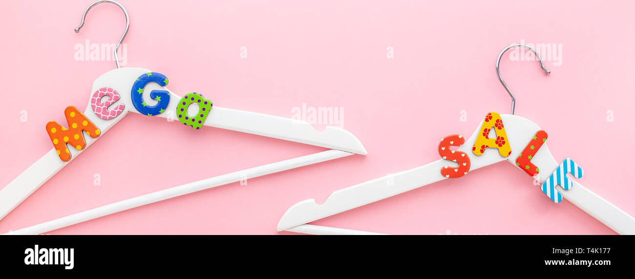 Creative vista superiore piatto bianco laici i portabiti in legno mega vendita testo rosa pastello sfondo spazio copia stile minimalista. Il modello femminile di moda blog soci Foto Stock