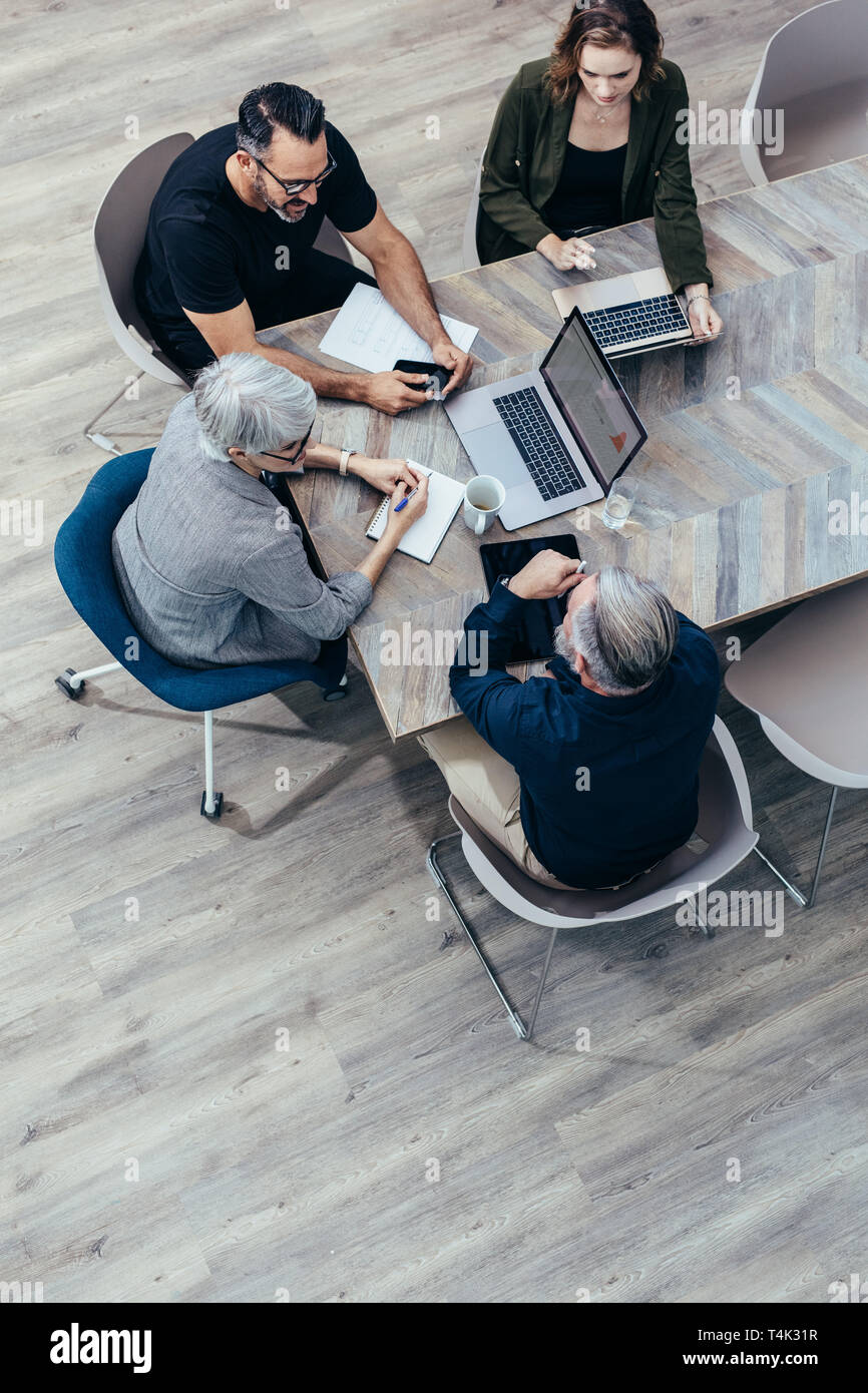 Vista superiore del team aziendale a discutere attorno ad un tavolo in ufficio. Un gruppo di persone di affari avente una riunione di brainstorming. Foto Stock