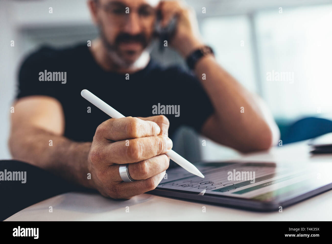 Imprenditore lavora su tavoletta digitale e parlando al cellulare. Imprenditore occupato a lavorare in ufficio , focus sulla tavoletta digitale e penna stilo. Foto Stock