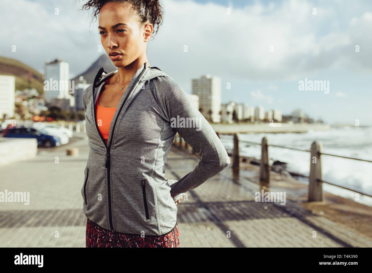 Montare la giovane donna stretching la gamba al lungomare. Sano giovane femmina la sua distensione dei muscoli delle gambe prima di correre. Foto Stock