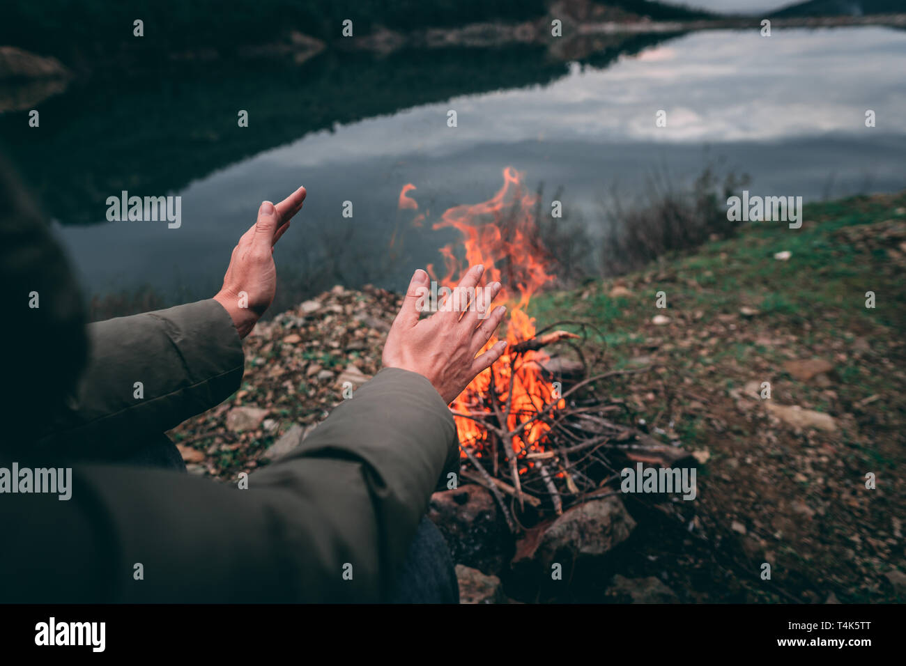 Le mani della giovane donna riscaldata dal fuoco di campo.le parti del corpo della femmina adulta in natura. Camping. Foto Stock