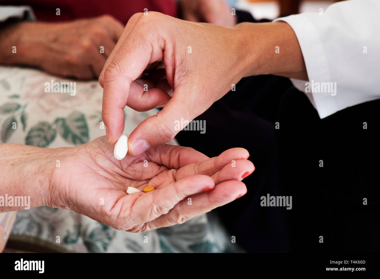 Primo piano di un medico caucasica uomo in camice bianco, dando alcune pillole a un senior caucasian paziente donna, a casa sua o in una casa di cura e una cau Foto Stock