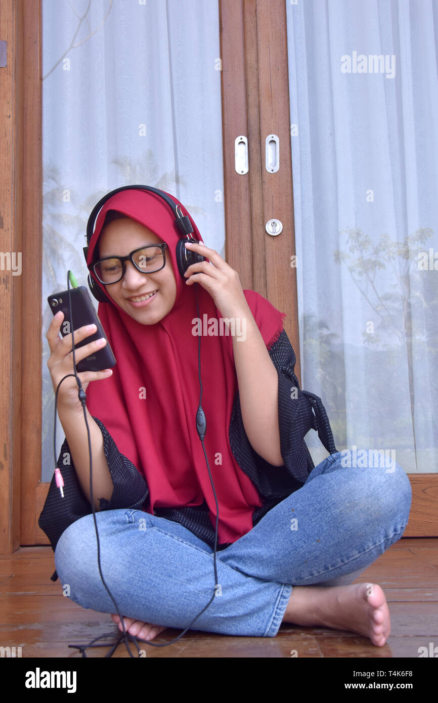 Musulmani asiatici, adolescenti con un sorriso utilizzando Mobilephone per ascoltare musica e selfies per scattare foto di loro Foto Stock