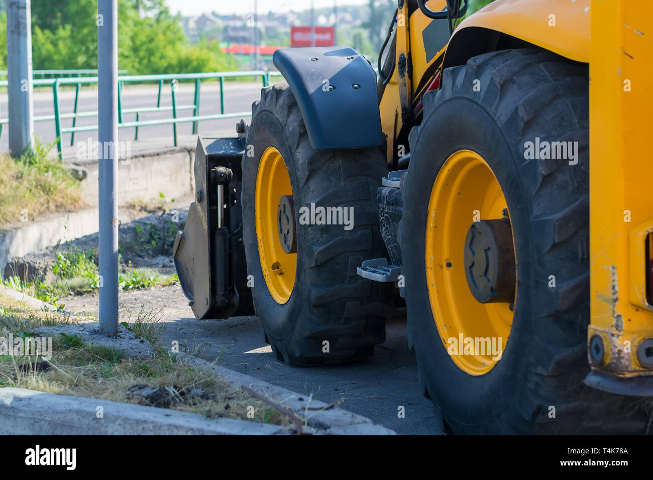 Enormi ruote del trattore, classificatore sul lato della strada di città vicino alla strada Foto Stock
