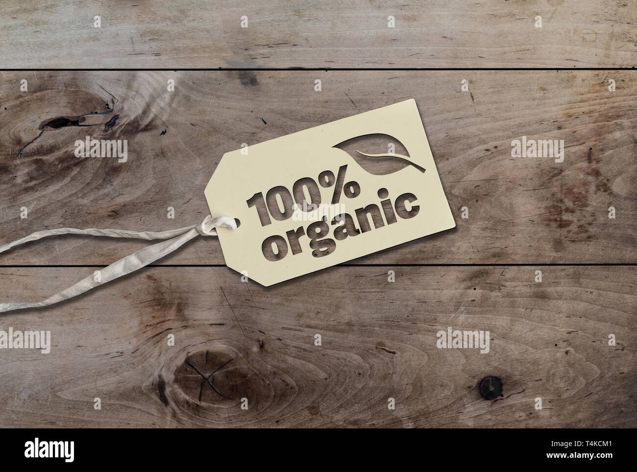 White hang tag etichetta cartone stringa con attaccato un testo 100% organic su tavola in legno rustico Foto Stock