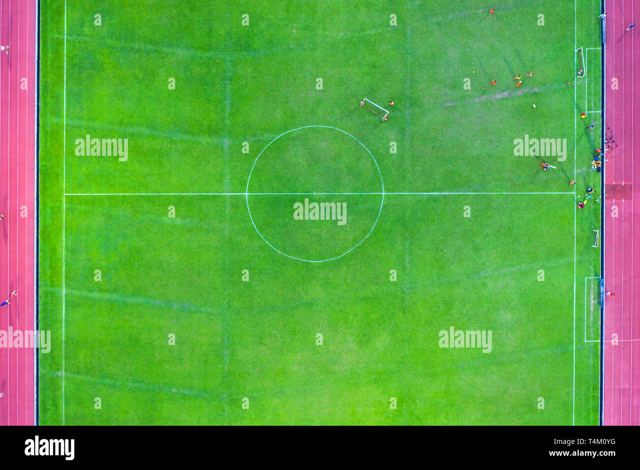 Prospettiva alternativa vista aerea del campo da calcio in medio con i giocatori della formazione, attaccato con erba vera e binari di scorrimento sul lato. Foto Stock