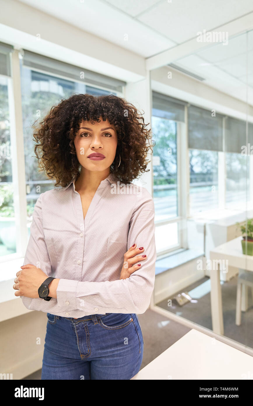 Giovane donna come un fiducioso imprenditrice e donna di carriera con bracci incrociati Foto Stock