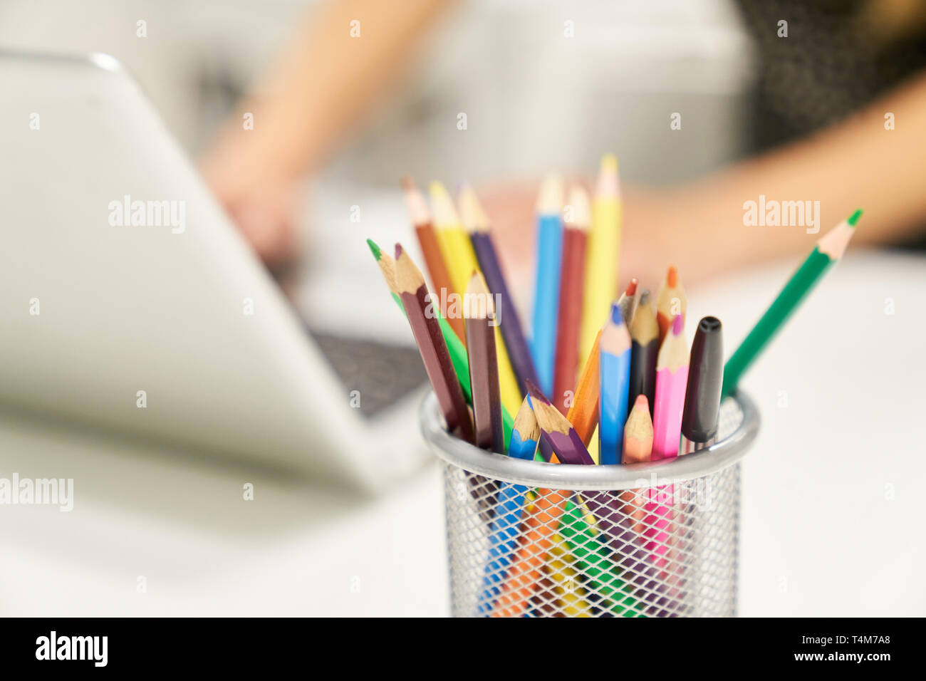 Matite colorate accanto al laptop sulla scrivania come un simbolo di creatività e design Foto Stock