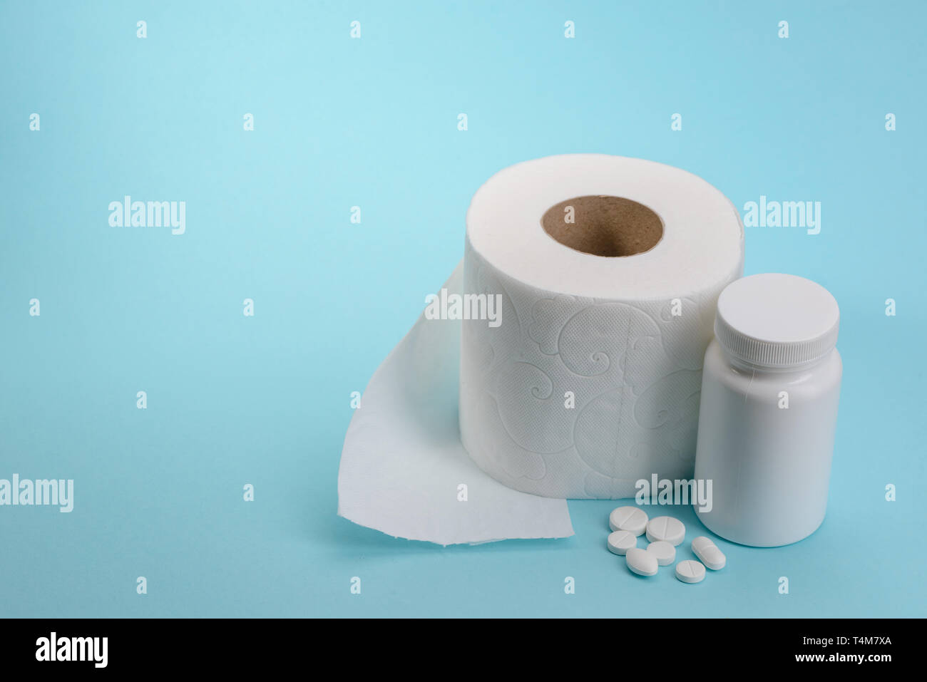 Carta igienica rotolo e pillole su sfondo blu con una copia dello spazio. Come liberarsi di stitichezza. Un trattamento efficace per il disturbo digestivo. Foto Stock