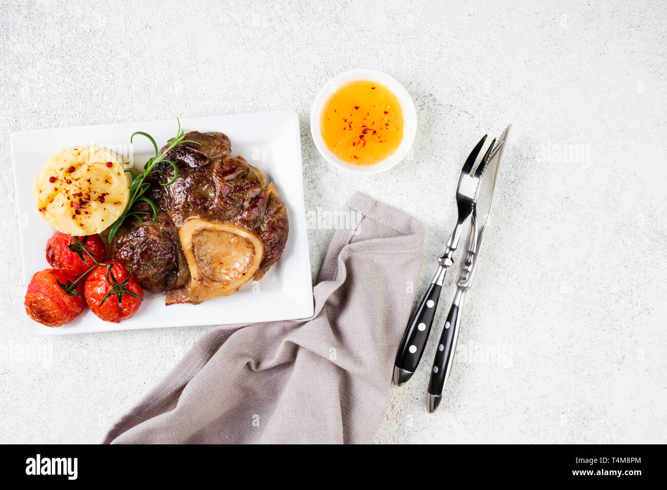 Bistecca di manzo osso bucco con purè di patate e pomodori sul tavolo. Il piatto di carne. Vista superiore, spazio di copia Foto Stock