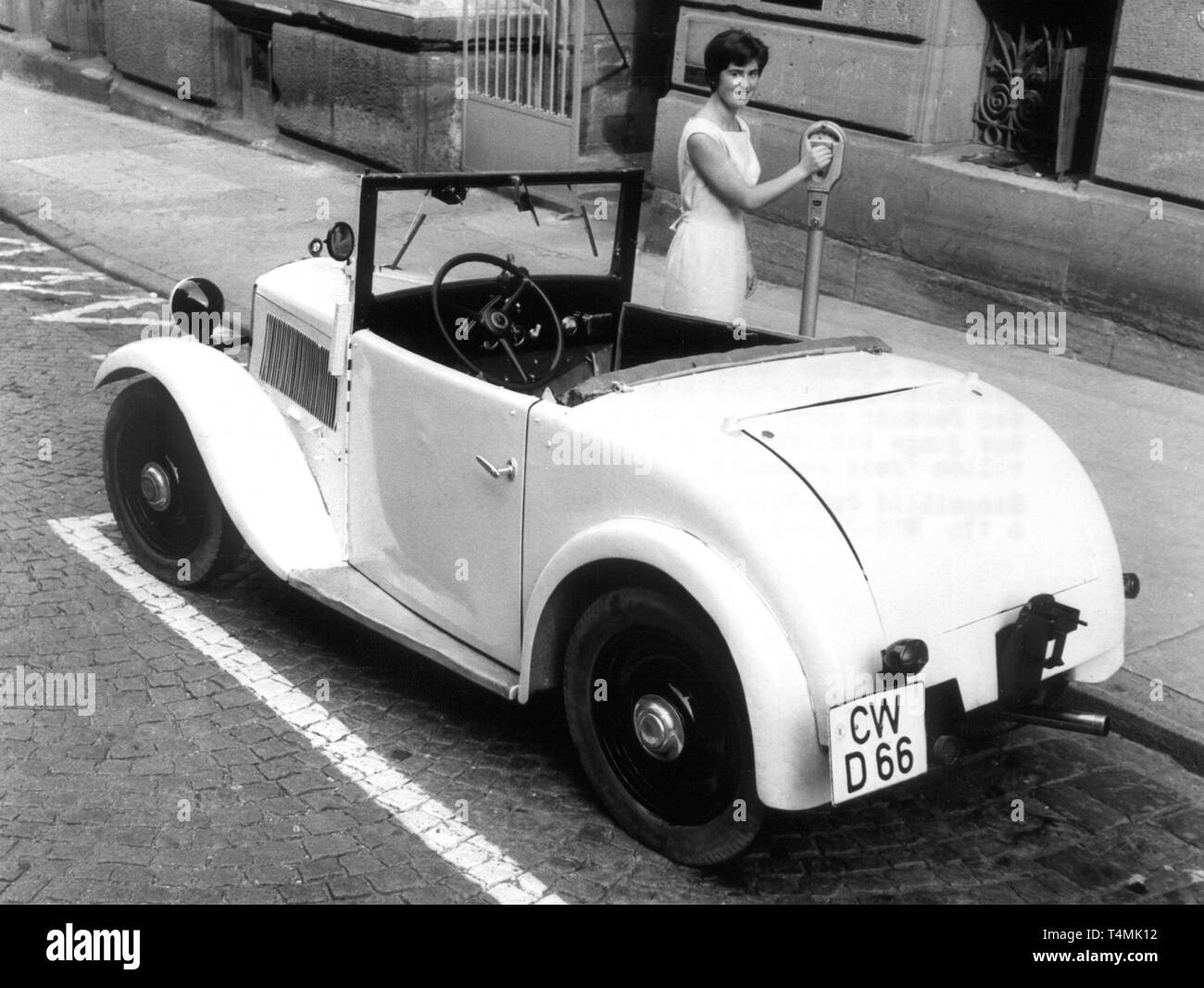 Il conducente di un 'Dixi' getta un centesimo in un parchimetro, fotografata nel 1958. | Utilizzo di tutto il mondo Foto Stock