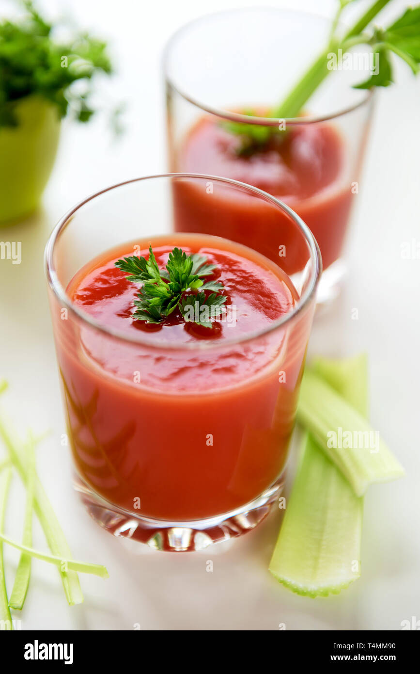 Il succo di pomodoro in un bicchiere con foglie di prezzemolo e sedano. Foto Stock
