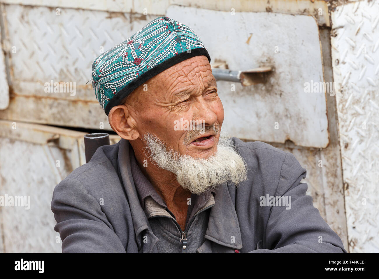Ritratto di anziani, barbuto Uyghur uomo che indossa un tradizionale doppa (HAT). Catturato in un mercato di Kashgar (provincia dello Xinjiang, Cina) Foto Stock