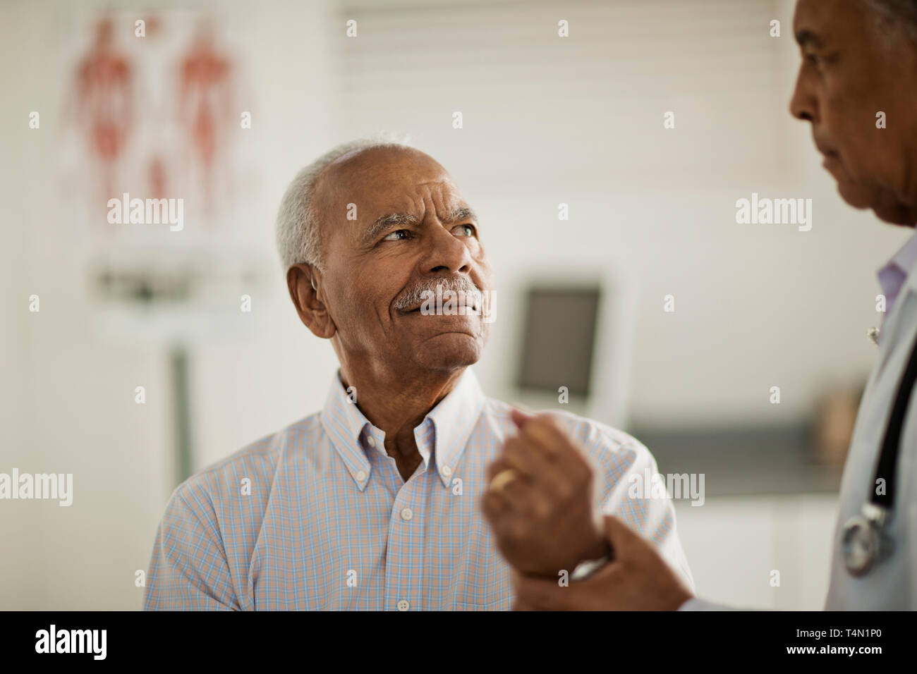 L'uomo anziano avente il suo braccio esaminato da un medico maschio all'interno di un ambulatorio medico. Foto Stock