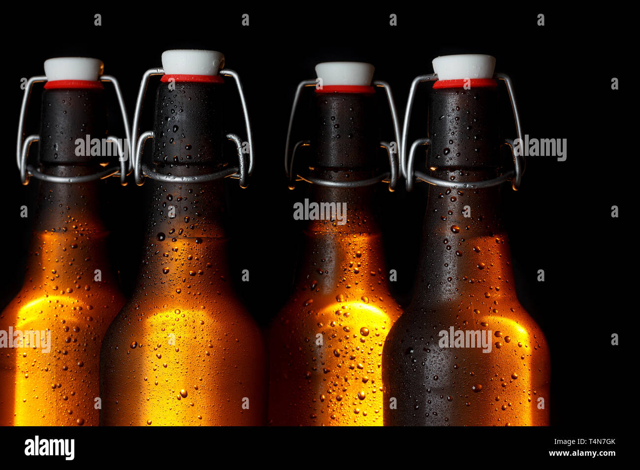 Golden incandescente bottiglie di birra su sfondo scuro Foto Stock