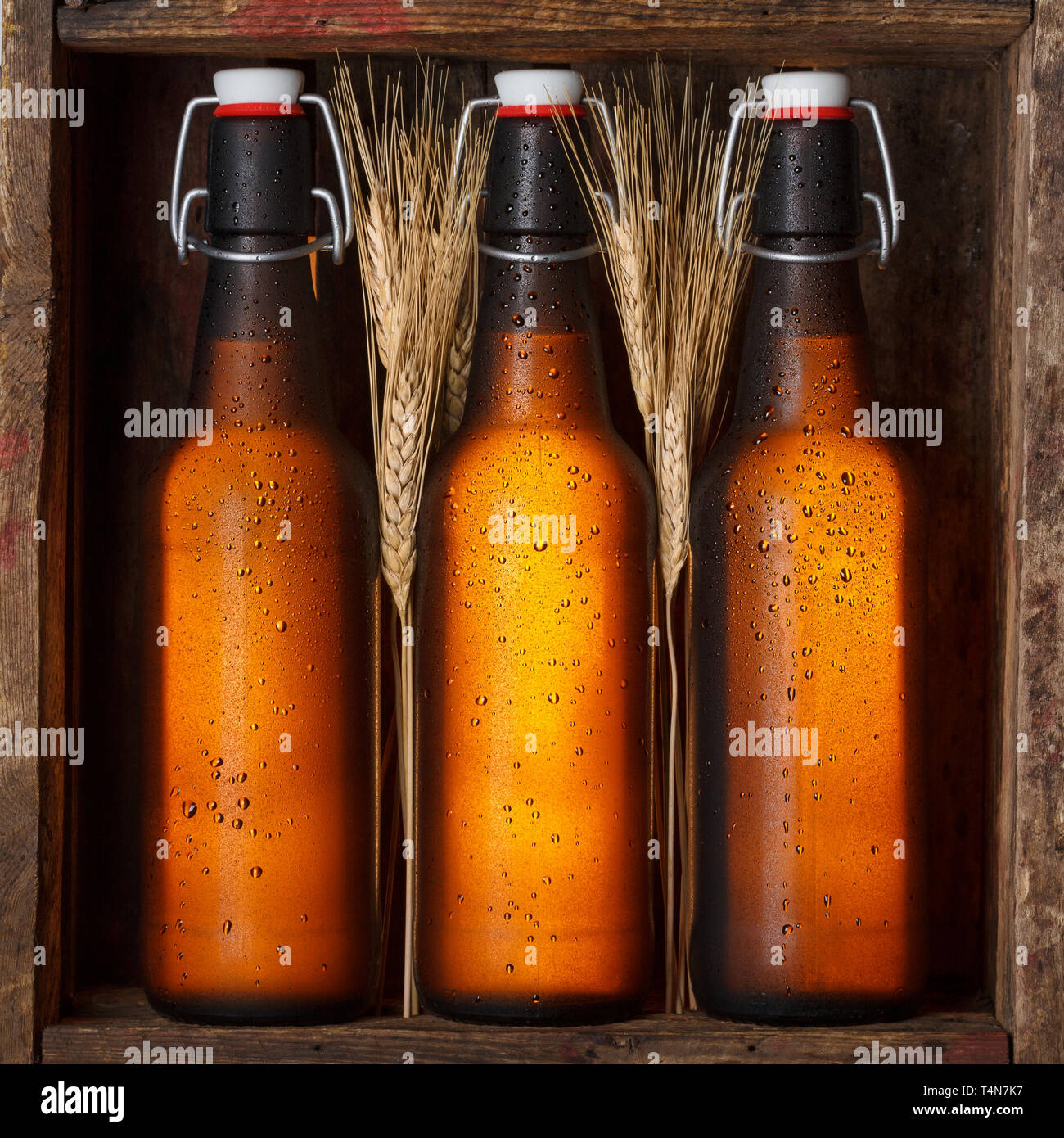 Le bottiglie di birra con steli di grano nella vecchia gabbia in legno ancora vita Foto Stock