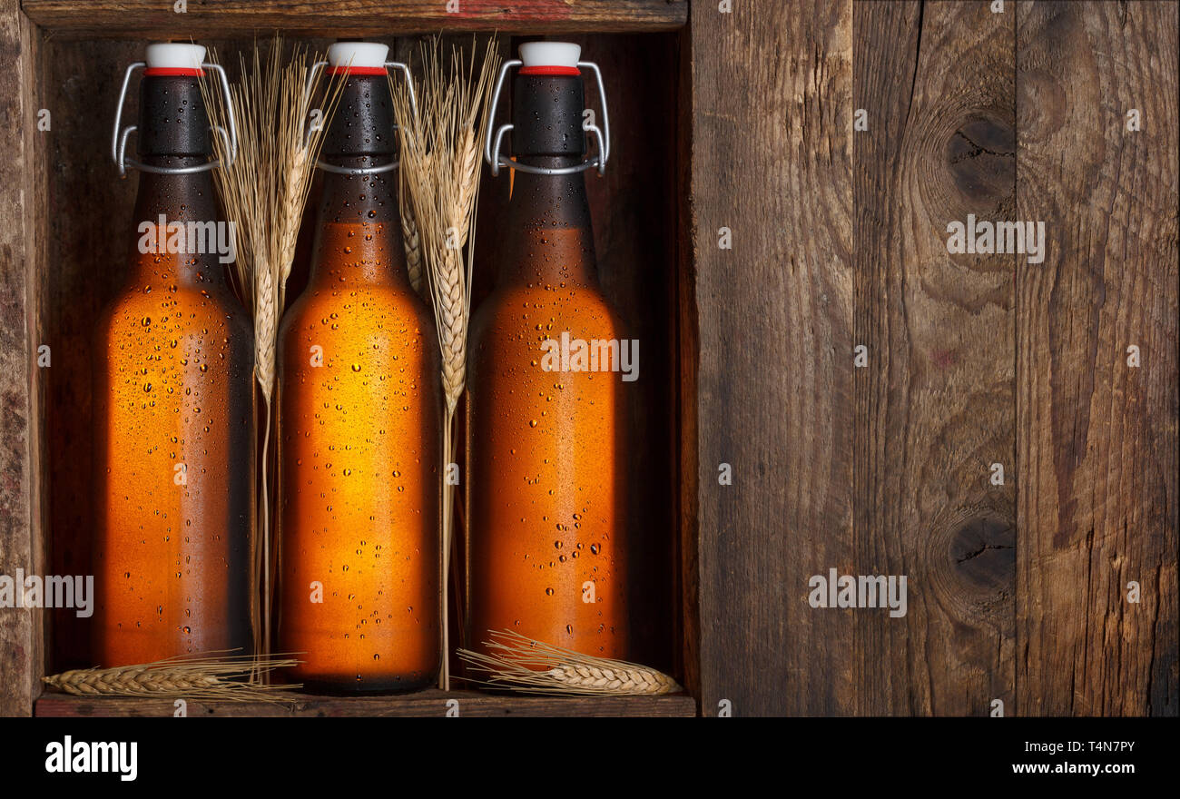 Le bottiglie di birra con steli di grano nella vecchia gabbia in legno ancora in vita, con spazio di copia Foto Stock