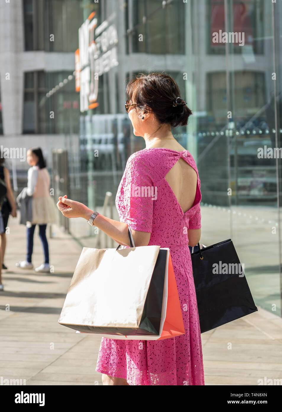 Una donna asiatica shopping con molti dei sacchi in mano. Foto Stock