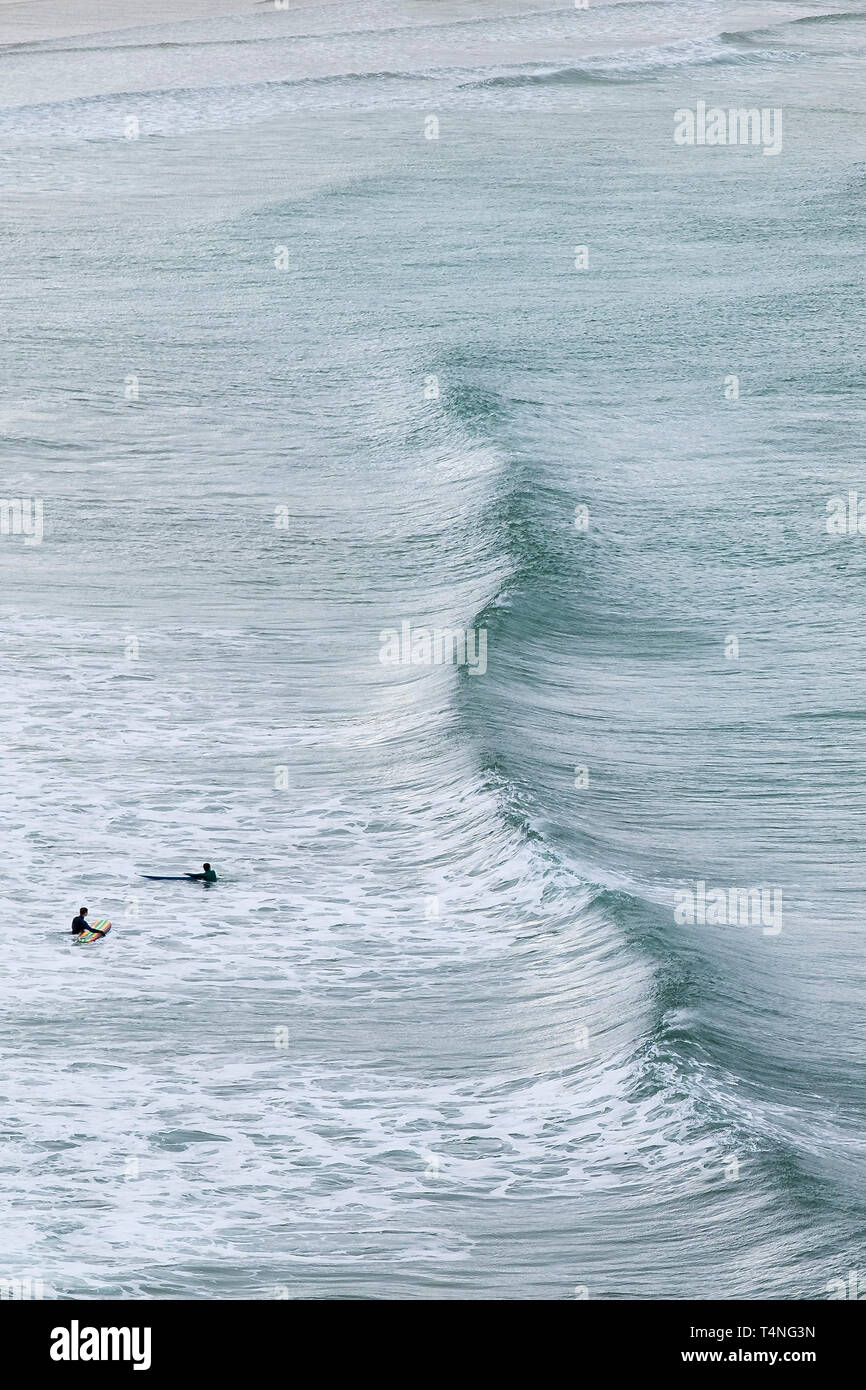 Surfers in attesa di un onda in arrivo a Crantock Beach in Newquay in Cornovaglia. Foto Stock
