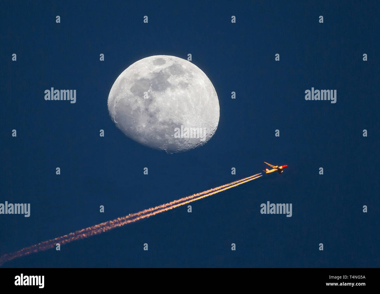 Un aereo di linea ad alta altitudine passa da un waxing gibbous moon al tramonto. Foto Stock