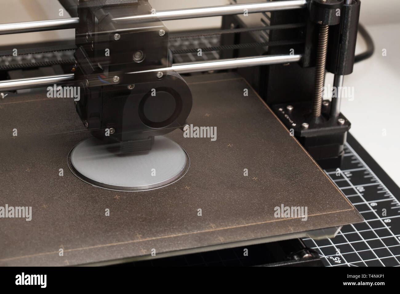 Un primo piano di una stampante 3D nel processo di stampa di un prototipo di design da un file digitale mentre mostrando l'estrusore in movimento. Foto Stock
