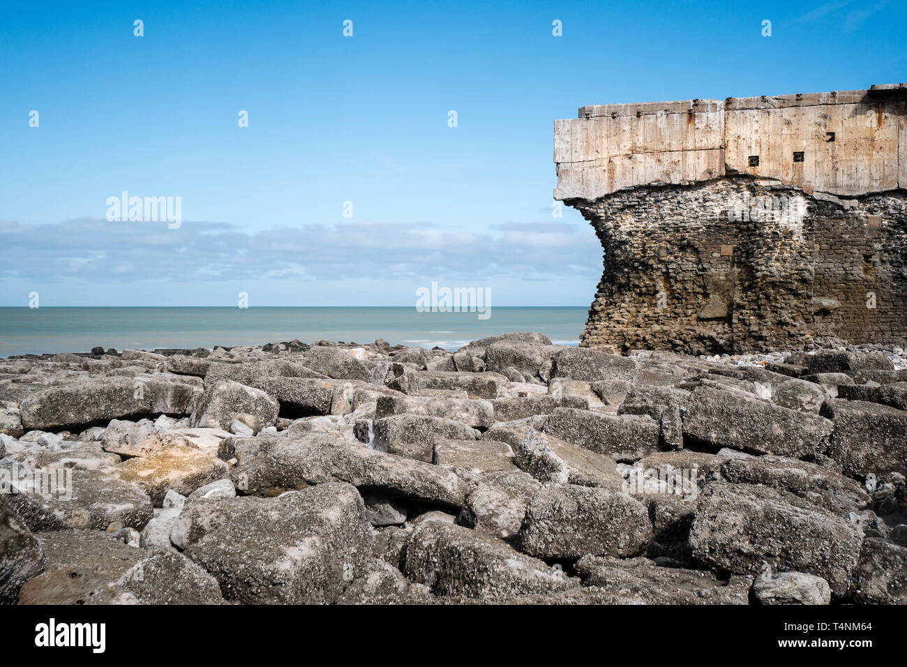 Antico fortilizio in corrispondenza della linea di galleggiamento con grandi rocce in primo piano Foto Stock