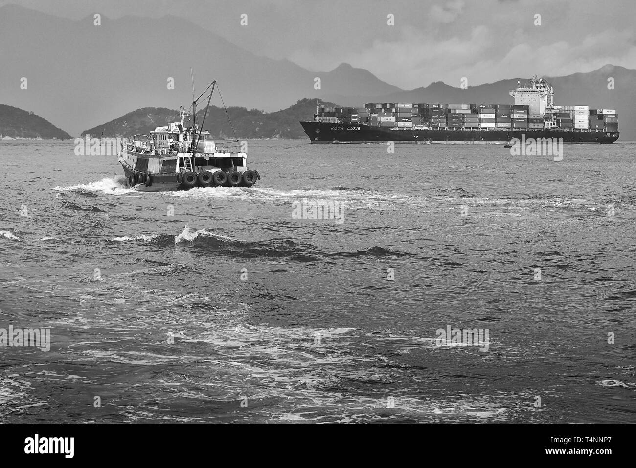 Foto in bianco e nero della nave portacontainer KOTA LUKIS, lascia i terminali per container Kwai Tsing a Hong Kong e si dirige verso il canale Lamma orientale Foto Stock