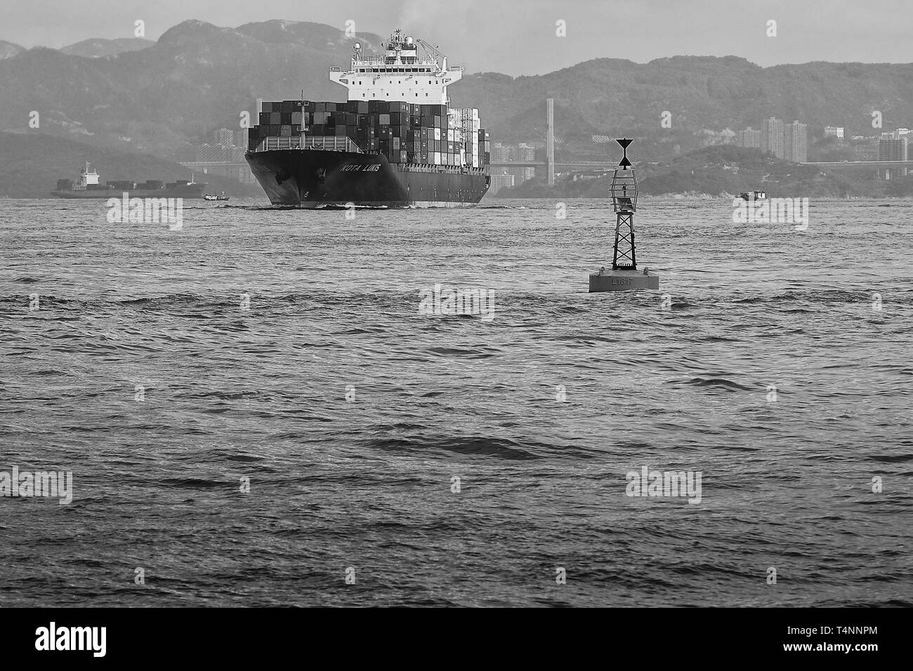 Foto in bianco e nero della nave portacontainer KOTA LUKIS, che lascia i terminal dei container Kwai Tsing, Hong Kong e si dirige verso il canale Lamma orientale Foto Stock
