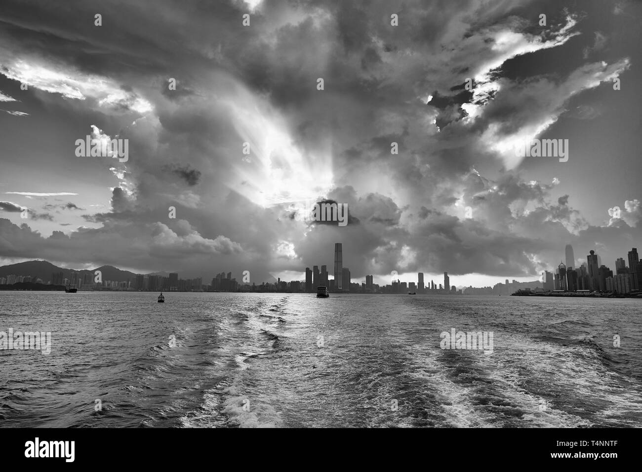 Foto Moody in bianco e nero di Una Giant Tropical Storm Cloud (cumulonimbus), illuminata dal Sol Levante, sopra Victoria Harbour, Hong Kong. Foto Stock