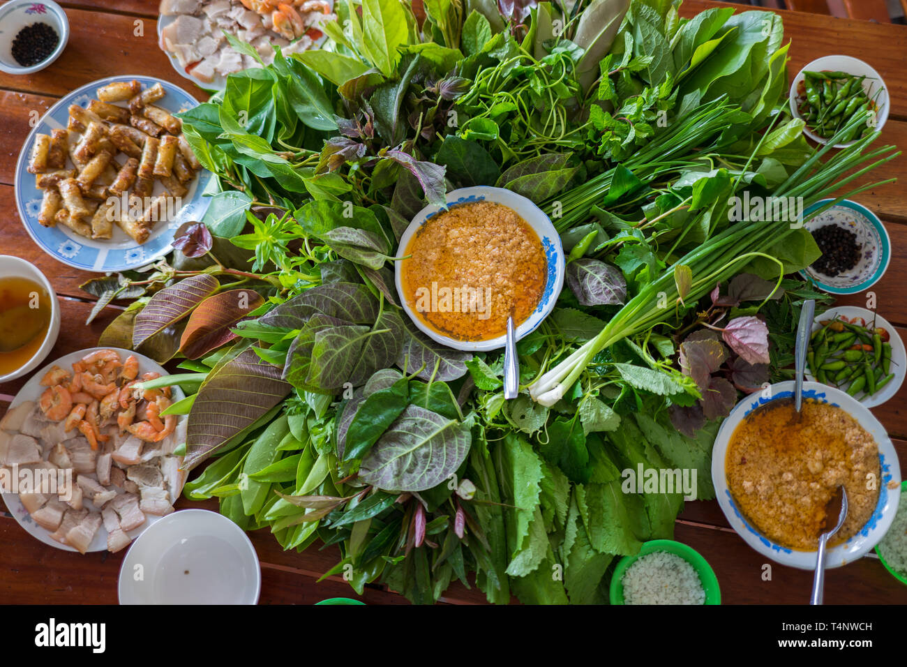 Peculiare insalata di erbe in Kon Tum, Vietnam. Utilizzando le foglie per rendere un cono-contenitore sagomato per mettere il cibo in e utilizzare un po' di bacon, fritto di gamberetti, battery slice Foto Stock