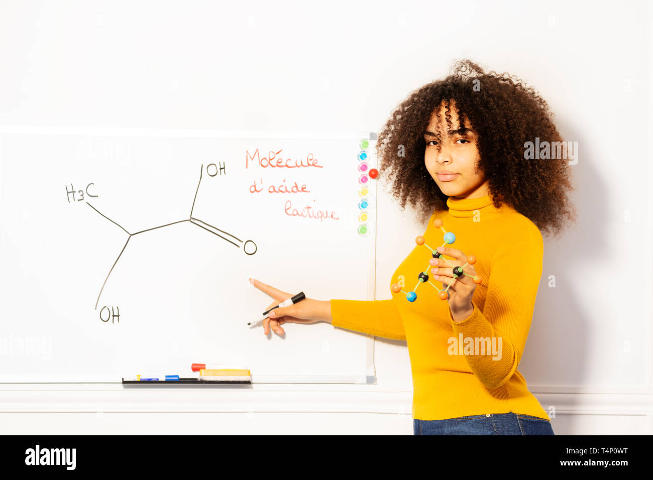 Studente ragazza mostra di molecola di acido sulla scrivania bianca Foto Stock