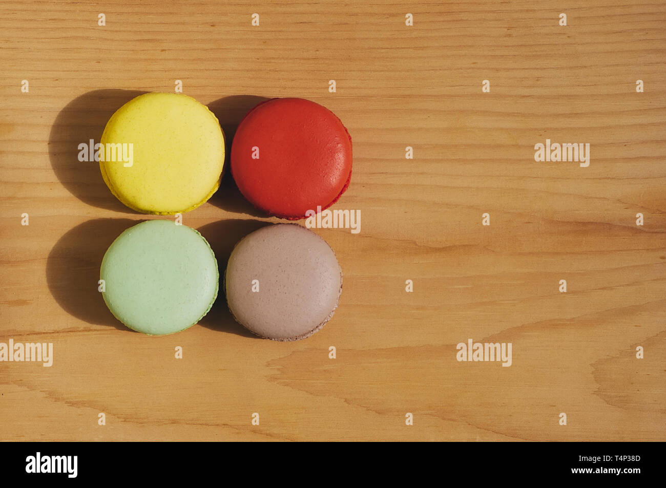 Quattro gustosi colorati macarons francese isolato su texture di legno Foto Stock