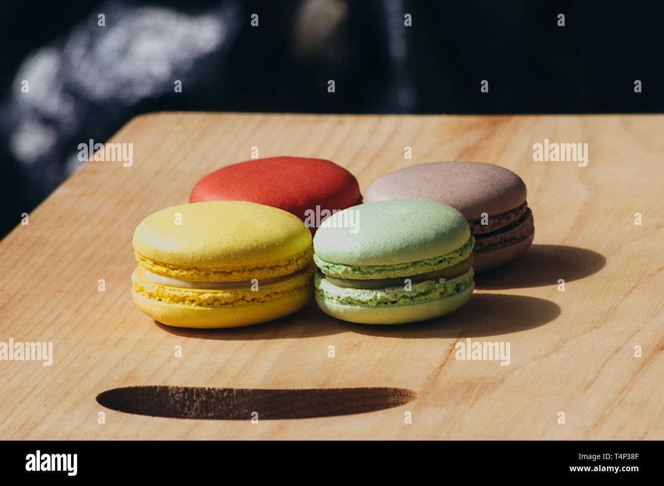 Quattro gustosi colorati macarons francese isolato su texture di legno Foto Stock