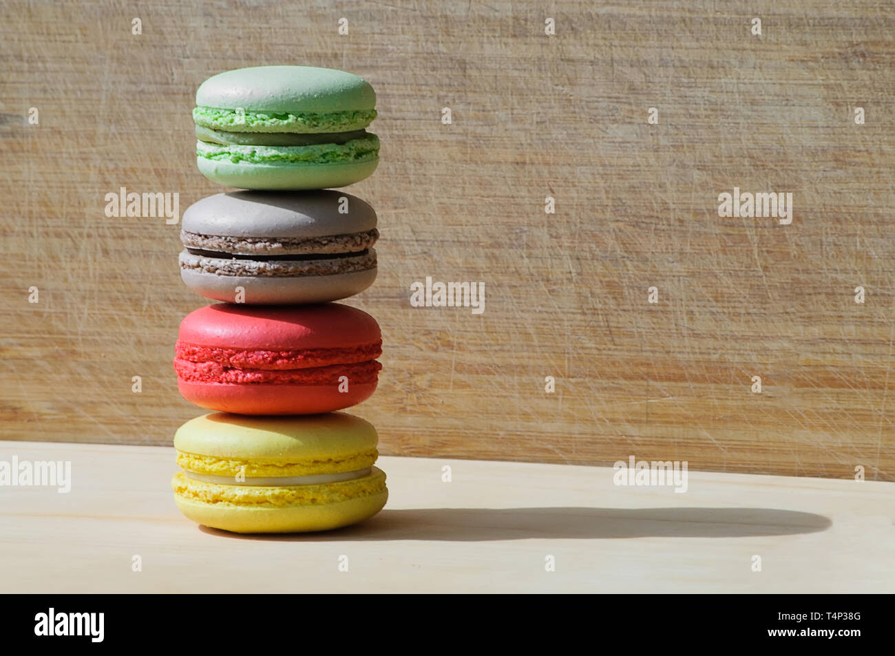 Quattro gustosi colorati macarons francese isolato su texture di legno Foto Stock