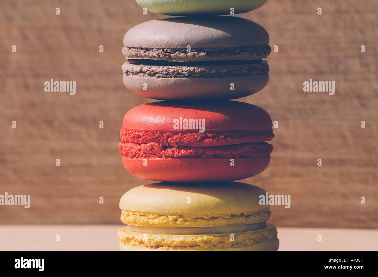 Quattro gustosi colorati macarons francese isolato su texture di legno Foto Stock