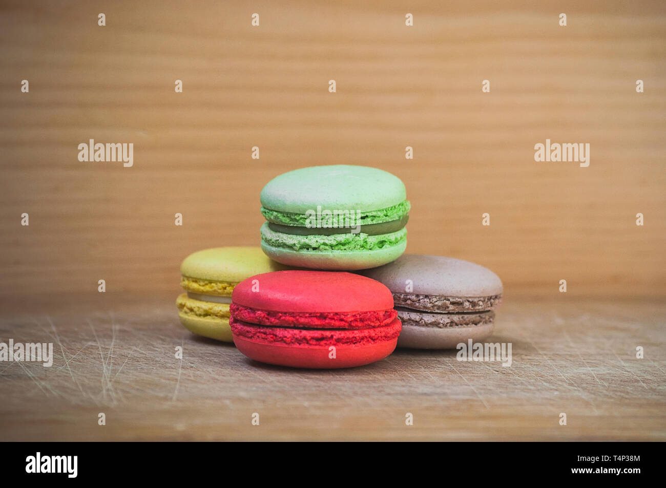 Quattro gustosi colorati macarons francese isolato su texture di legno Foto Stock