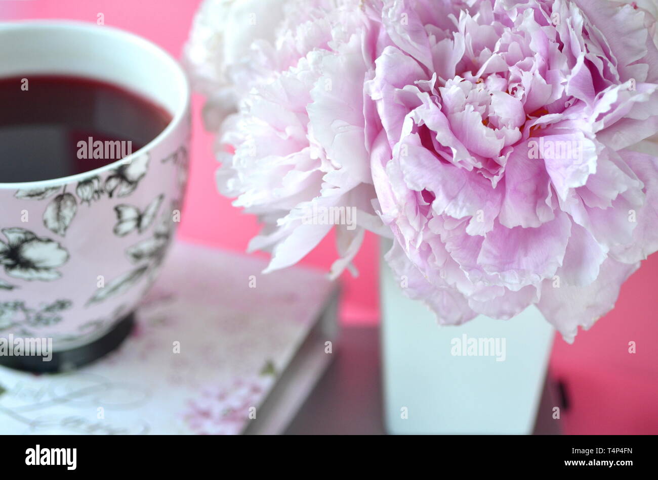 Elegante femminile in stile desktop - rilassamento, lettura, scrittura creativa, l'apprendimento e il concetto di journaling con peonie rosa, caffè, accessori chic Foto Stock