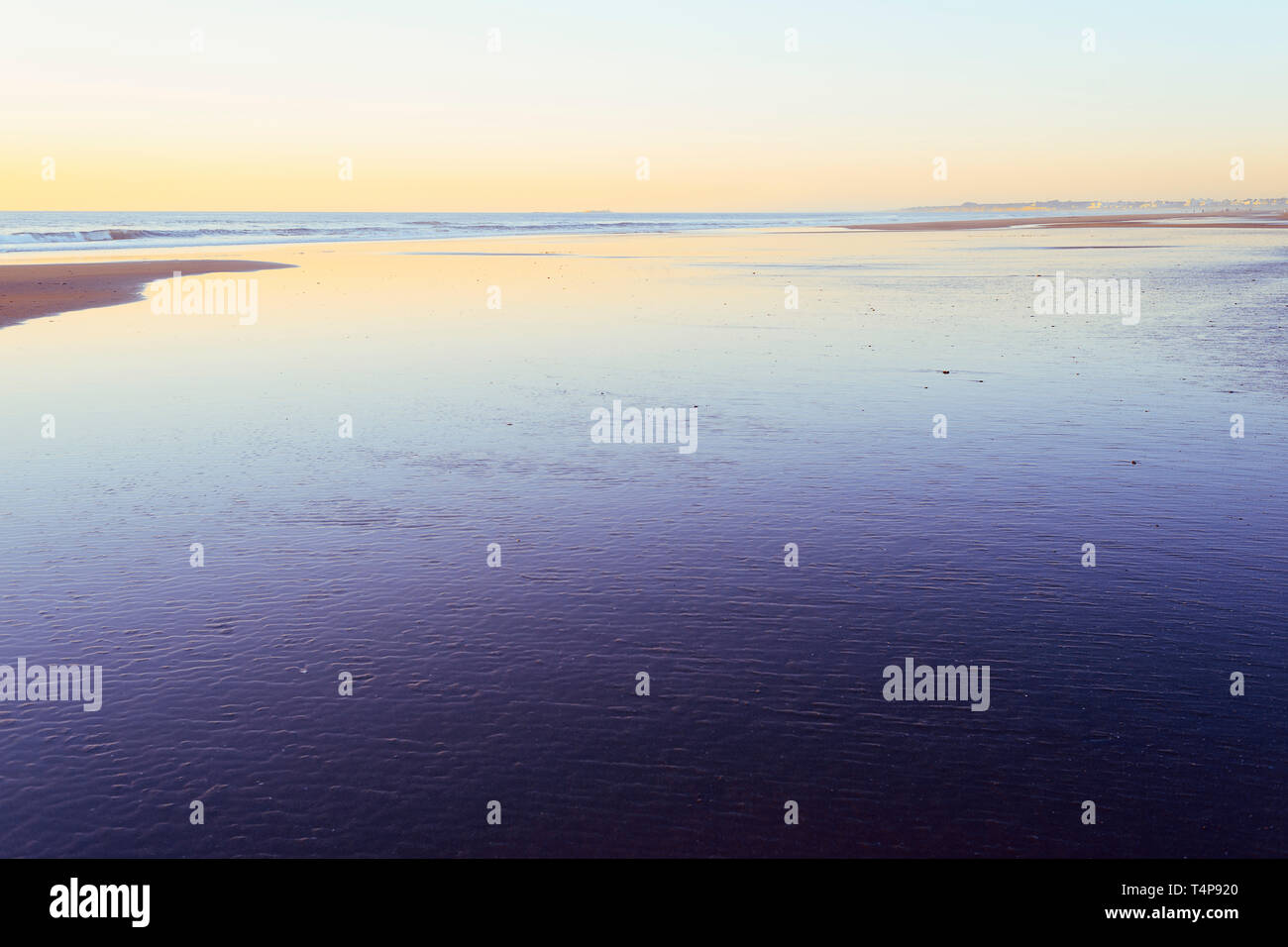 Tramonto su una solitaria spiaggia inondata dalla bassa marea, stile minimalista Foto Stock