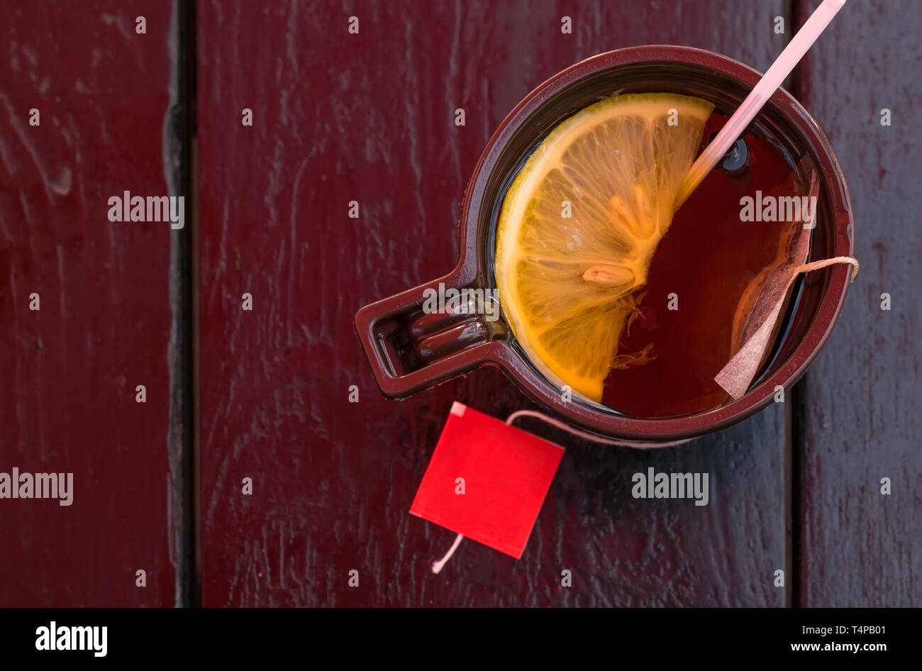 La coppa di plastica con tè e limone sul legno vecchio tavolo Foto Stock