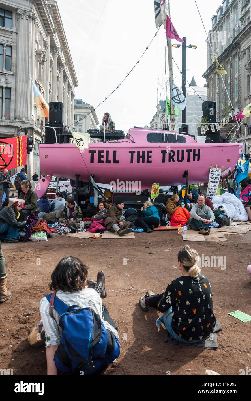 "Estinzione Ribellione dei manifestanti contro il cambiamento climatico il blocco e occupare Oxford Circus con un rosa luminoso yacht visualizzando un "dire la verità " segno. Foto Stock