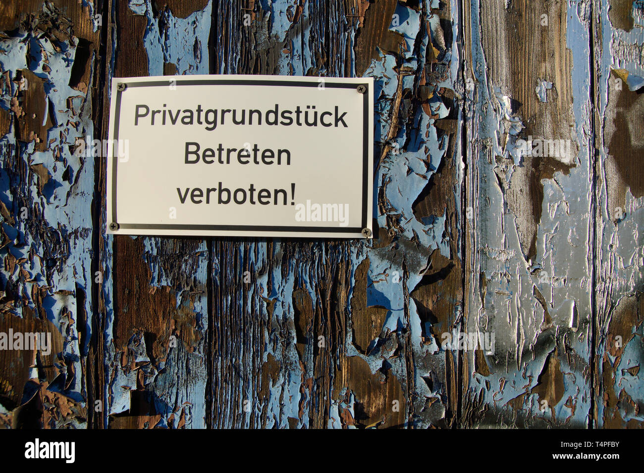 Schild Privatgrunstück Betreten verboten an Holtüre mit abblätterndem lack Foto Stock