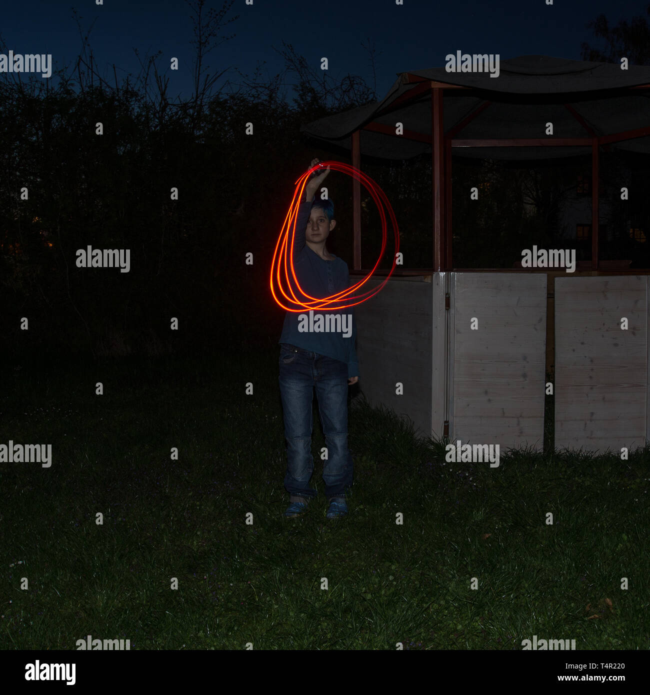 Un ragazzo forma la lettera 'D' con la sua torcia elettrica la sera Foto Stock