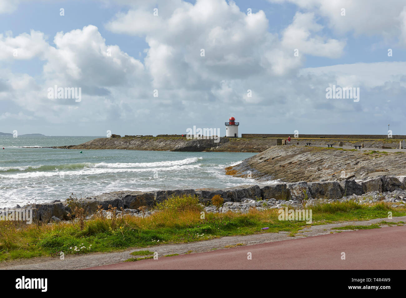 Burry Port frangiflutti e faro del piccolo vecchio porto di carbone, attualmente utilizzato per la ricreazione, con piccole onde provenienti su per la spiaggia. Il Galles. Foto Stock
